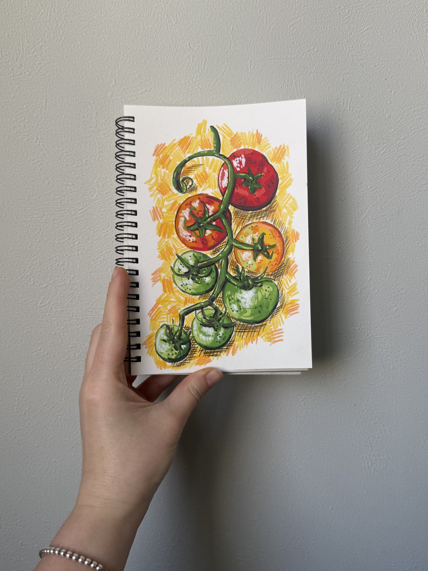 Tomato food illustration in a sketchbook made with ENMY acrylic markers, showing opaque red, orange, and green colour layers with visible pencil details.
