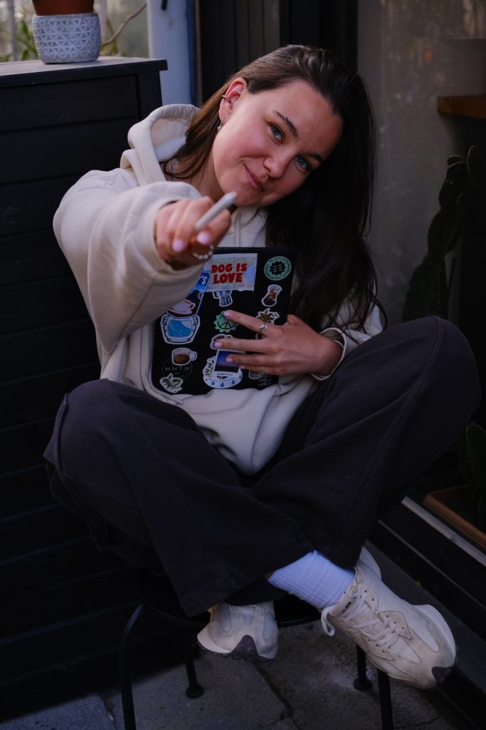 Adelya holding her sticker-covered iPad Pro and Apple Pencil in the studio.