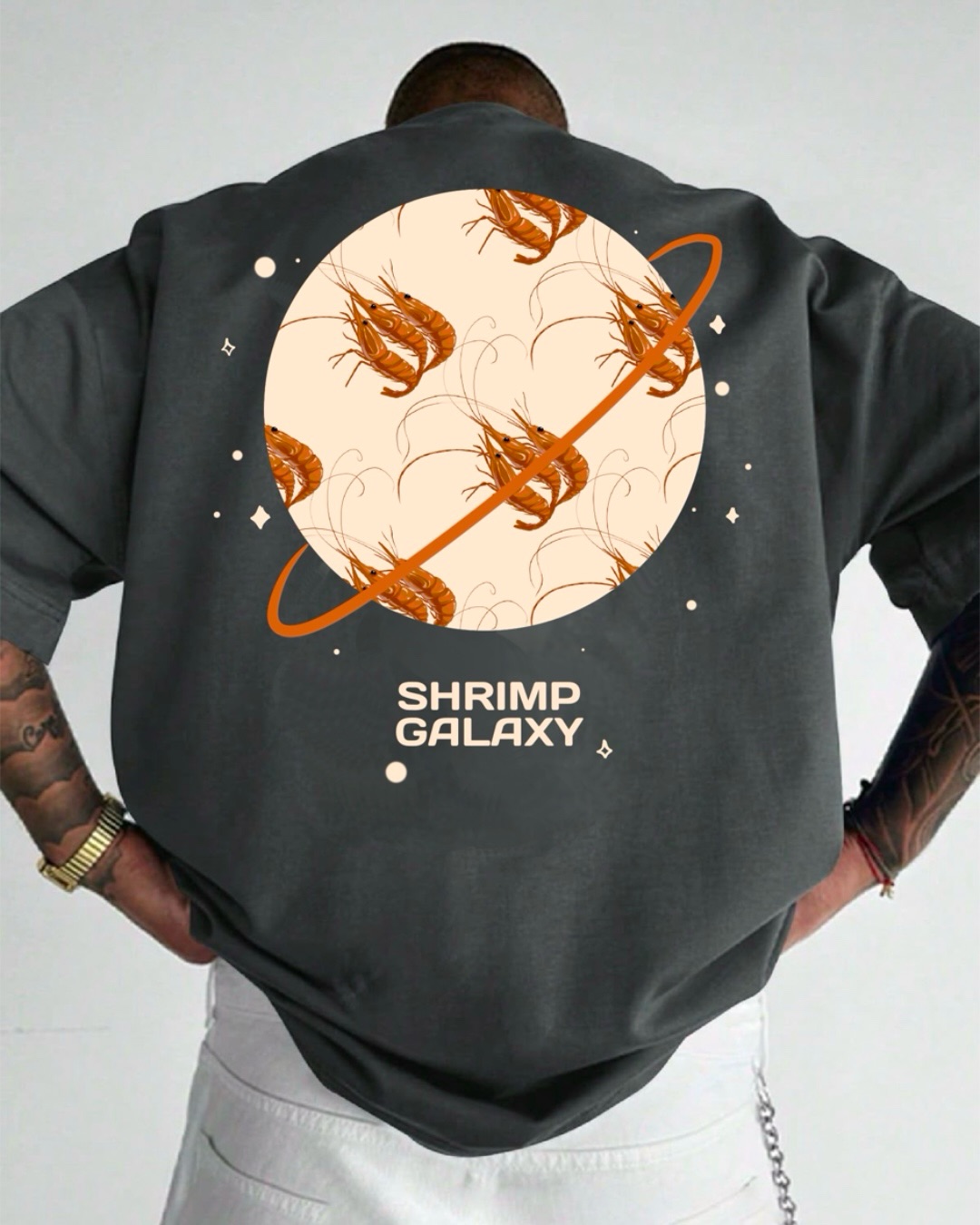 Dark grey shirt mockup with a circular shrimp pattern framed as a ringed planet, small stars, and the words Shrimp Galaxy.